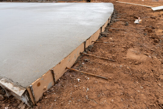 Perspective close-up of freshly leveled concrete slab with wooden formwork and dowel rebar bars