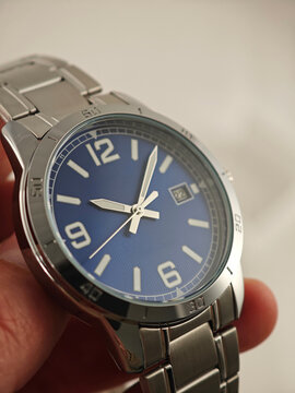 Man Wearing Elegant Wristwatch Outdoors. Man&rsquo;s wrist wearing a sophisticated analog watch with a blue dial and silver case