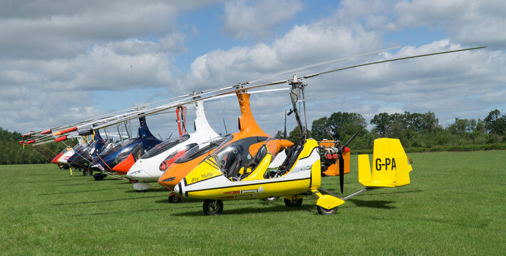 Row of Gyrocopter - Autogyros  parked on grass.