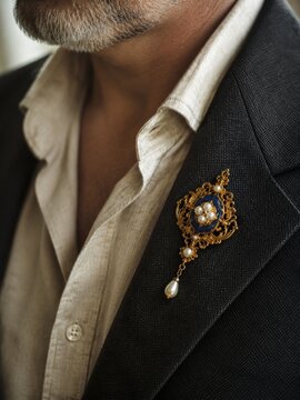 Vintage gold brooch with pearls on a man's suit lapel close-up fashion jewelry detail
