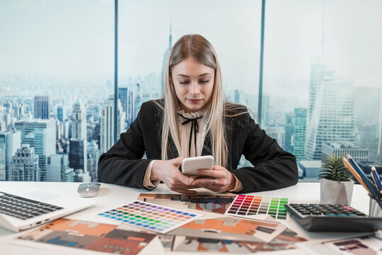 Young caucasian female engineer or designer drawing a blue print with color catalog