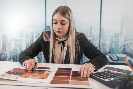 Female designer work at office with house plan for renovation, choose best color in wooden sampler