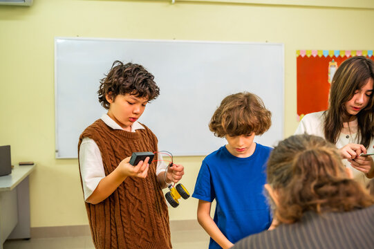 Group of curious kindergarten boys and girls assembling robot with guidance from senior male teacher in international school classroom