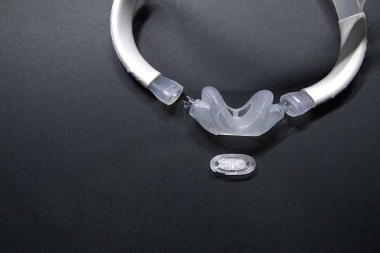 Disassembled CPAP nose mask or nasal CPAP cradle mask shows replaceable parts of CPAP headgear clip. Sleep apnea and sleep disorder with snoring stopped by respirator mask and CPAP machine treatment.