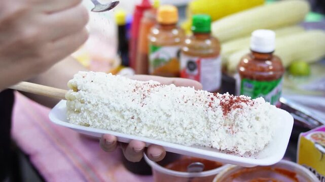 Close Up of Woman Adding Chili Powder to Mexican Street Corn in Slow Motion