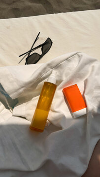 Sun care essentials arranged on a white towel at the beach
