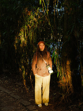Woman with camera standing near bamboo trees 