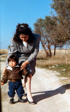 Mother teaching young child walking outdoors