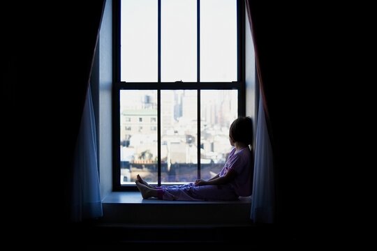 Child sits next to window in NYC