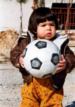 Young child holding soccer ball showing early interest in sports