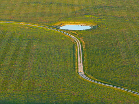 Narrow country lane alongside a small farm dam on rural farmland