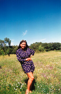 Woman smiling in polka dot dress outdoor in sunny field