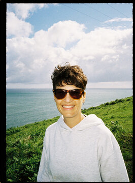 Woman smiling wearing sunglasses on green coast by the sea