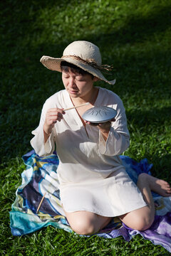 Chinese woman playing a hollow drum on the grass