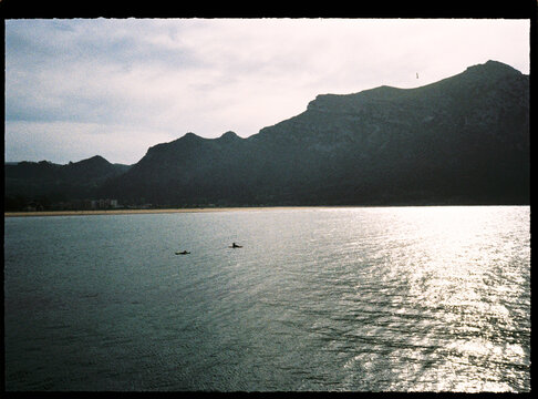 People kayaking on calm water with mountain background