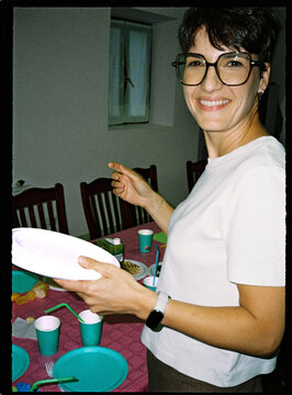 Smiling woman holding plates preparing casual home party