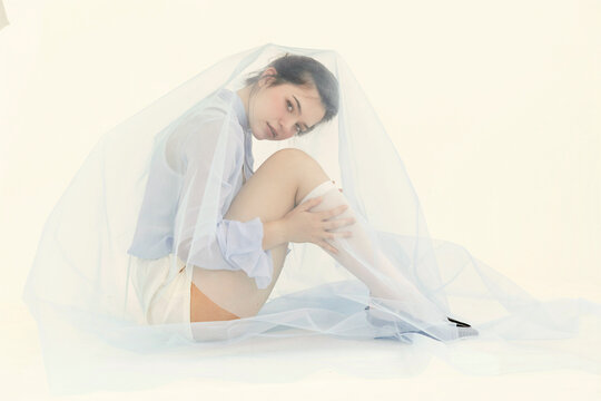 Woman sitting under sheer blue fabric