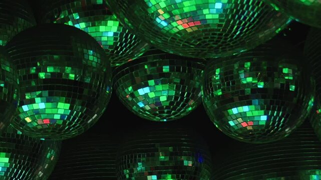Shimmering disco balls reflect a vibrant kaleidoscope of colors, creating an electric atmosphere for a joyous Christmas celebration inside a lively nightclub. The festive light dances around the room.
