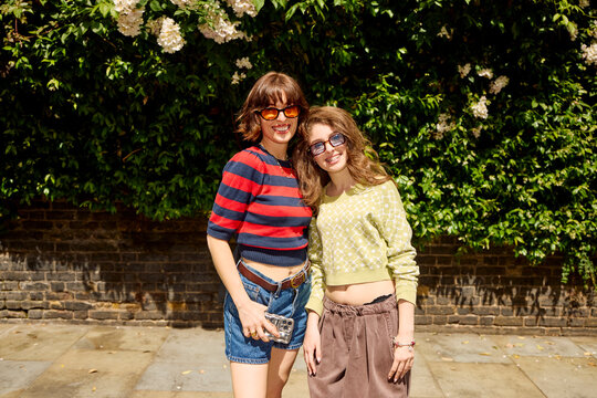 Trendy women pose for a portrait against the green wall