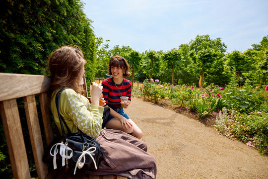 Friends relish a sunny day in a city park filled with flowers.