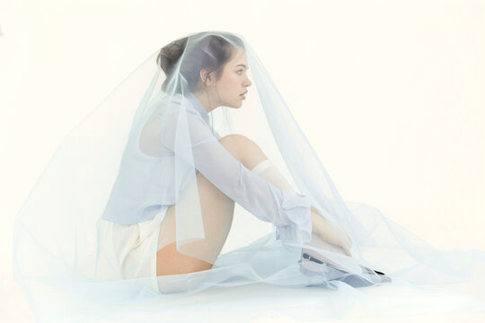 Woman sitting wrapped in blue tulle veil