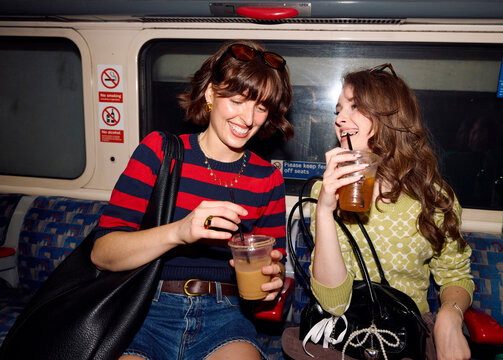 Mother and daughter enjoy drinks on a train ride in the city