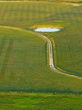 Narrow country lane alongside a small farm dam on rural farmland