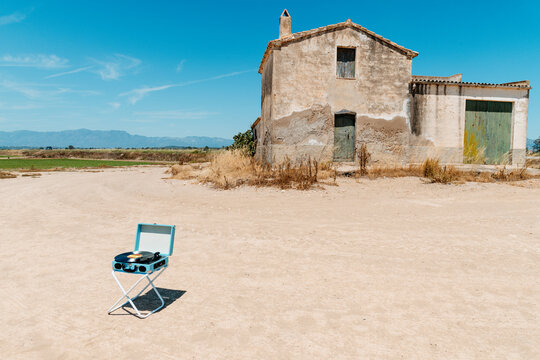 in a vast dusty yard, a record player spins beside a farmhouse