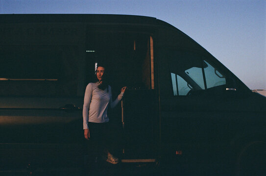 A woman standing beside a camper van during a road trip adventure.