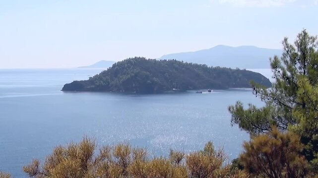 A breathtaking vista captures the serene beauty of Fethiye Bay in Turkey. Lush green islands dot the glistening blue waters, framed by distant hills and vibrant coastal flora.