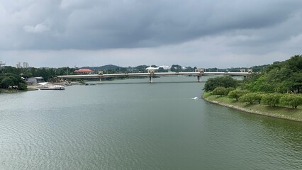 Bridge spanning a calm lake with surrounding parkland and dark clouds gathering overhead © MR HEPPY
