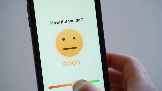 Hand holding smartphone showing customer feedback survey with smiley face rating 