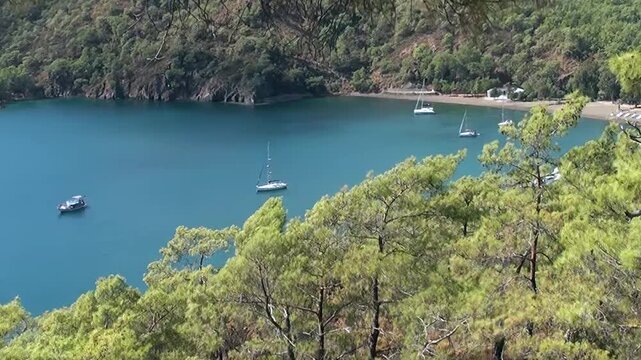 Breathtaking Oludeniz Bay, Turkey, captivates with serene beauty. Sailboats and a motor yacht gracefully drift on crystal-clear azure waters.