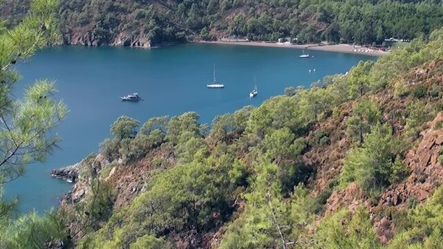 Sunlight graces Oludeniz Bay Turkey, revealing a stunning coastal panorama. Yachts and sailboats gracefully float on the calm, clear waters.