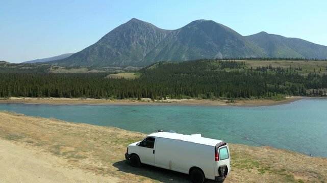 White camper van parked by Kusawa Lake drone aerial view in Yukon, Canada
