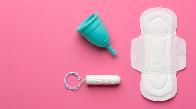 A collection of feminine hygiene products including a menstrual cup a tampon and a sanitary pad on pink