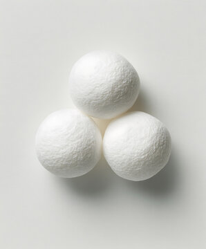 Three white mothballs rest against a light gray background showcasing a simple composition