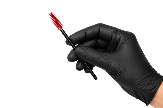 Hand in black protective glove holding a red spoolie brush for eyebrow and eyelash grooming on white background. Professional beauty salon, brow styling and makeup tool concept.