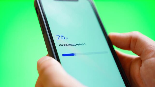 Hands holding smartphone with refund processing and refund issued on green background 