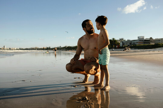 Father And Son Talking On Sunset Beach At Low Tide - Family Bonding And Summer Vacation