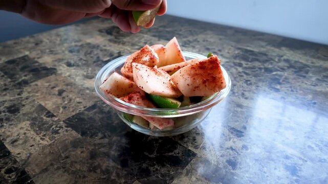 Squeezing fresh lime juice on mexican jicama and cucumber chili powder snack