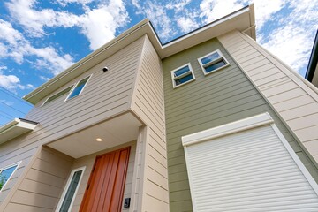 Fototapeta premium 青空に白い雲が広がるモダンな新築一戸建て住宅の外観イメージ