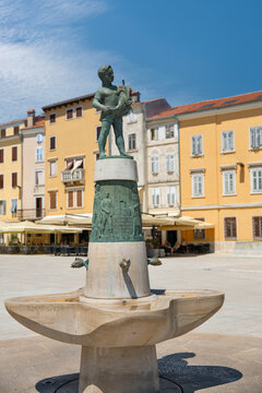 Bronze boy with fish fountain in Rovinj square, Croatia.