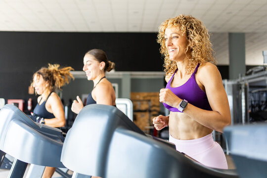 A group of women between 20 and 40 years old are running on a treadmill in a gym wearing sportswear. Concept of women running on a treadmill.
