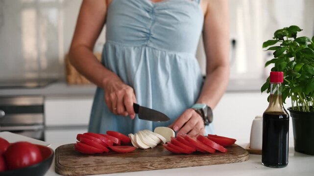 Young Woman Slides Mozzarella On A Cutting Board For A Fresh Vegetable Caprese Salad In The Kitchen
