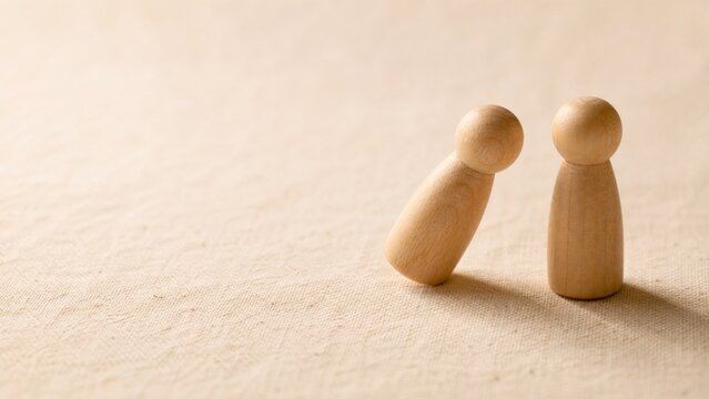 Two Wooden Figures Leaning Together Symbolizing Connection and Support