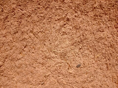 Traditional earthen wall texture with red clay and straw, Rough red clay earthen wall with straw texture