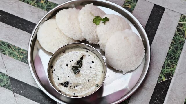Traditional Indian breakfast featuring steamed idli served with spiced sambar curry. Authentic South Indian cuisine prepared fresh. Garnished with cilantro. Perfect for food blogs, cooking shows, 