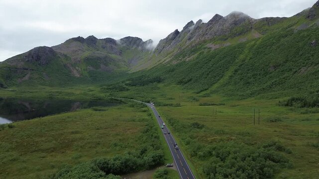 drone of road heading to a mountain in clouds in lofoten norway with traffic 