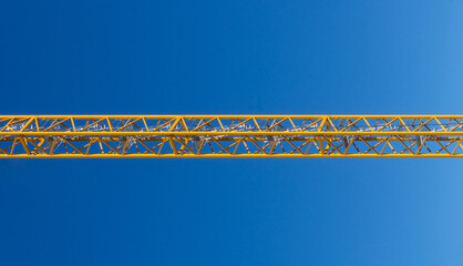Yellow construction crane boom structure against blue sky © photoopus